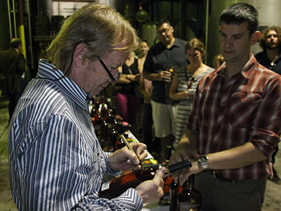 John Hall signs a bottle of Forty Creek Heart of Gold Canadian Whisky at the distillery on September 28, 2013. Image © 2013 by Mark Gillespie.