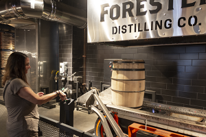 A visitor presses the button to start charring a whiskey barrel in the cooperage at the Old Forester Distillery on Whiskey Row in Louisville, Kentucky. File photo ©2020, Mark Gillespie/CaskStrength Media.